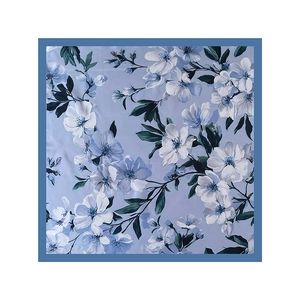 Flat lay detail of a floral satin square scarf with blue blossoms and dark navy borders