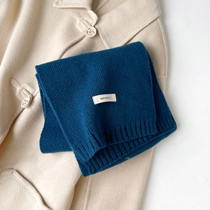 Dettaglio dell'etichetta 100% pura lana su una sciarpa in maglia spessa blu scuro
