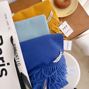 Détail de foulards unis effet cachemire avec franges et étiquettes de la marque