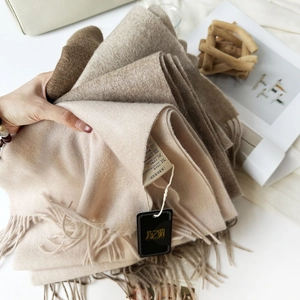 Detail of pure wool scarves in earth tones with soft fringes and authentic care labels