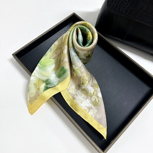 Floral print silk scarf with yellow borders displayed on a black elegant tray