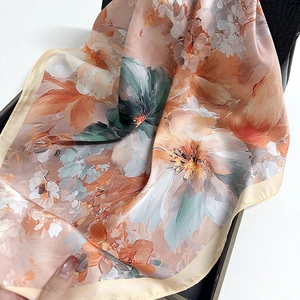 Elegant floral silk square scarf with peach and orange botanical prints on leather base