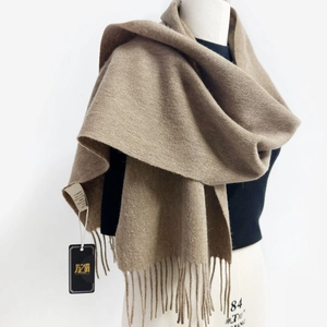 Detail view of camel Australian wool scarf with fringe on a white display mannequin