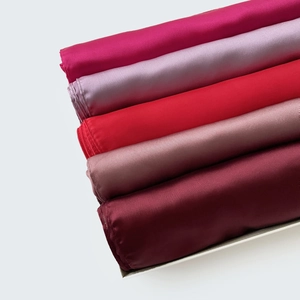 Detalle de pañuelos de satén de seda en varios tonos de rojo y morado con brillo suave