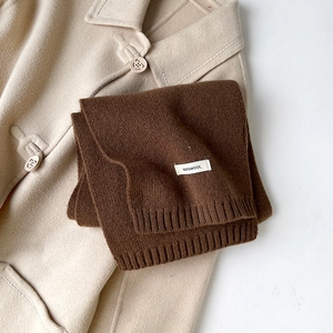 Dettaglio di una sciarpa in maglia marrone 100% lana con trama del tessuto ed etichetta