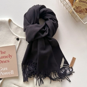 Gros plan sur la texture de l'écharpe à franges gris anthracite sur un manteau en laine
