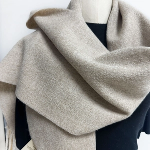 Detailed close-up of premium oatmeal wool scarf with soft knit texture and fringe edge