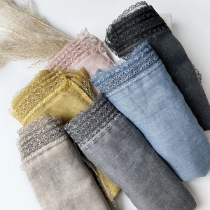 Detailed view of lightweight linen scarves featuring delicate lace borders in multiple colors
