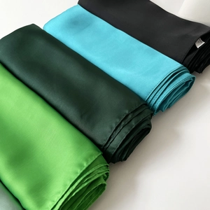 Detalle de pañuelos de satén liso en verde y negro con costuras de dobladillo fino