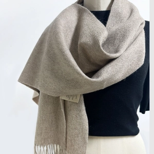 Close-up of light beige 100% Australian wool scarf featuring fine tassels and quality label
