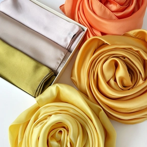 Detalle de pañuelos de satén sedoso en varios colores plegados en forma de rosas