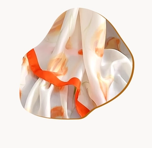 Détail d'un foulard en soie avec imprimé floral orange et texture satinée élégante