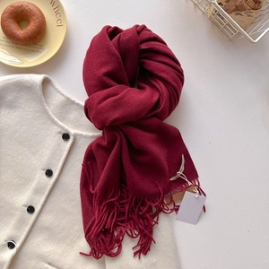 Détail d'une écharpe rouge foncé effet cachemire avec franges et maille couleur crème