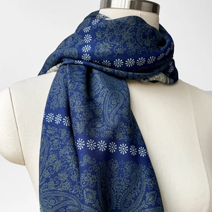 Dettaglio ravvicinato di motivi paisley e margherite su una sciarpa di seta blu navy su manichino