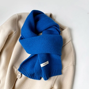 Dettaglio della trama della sciarpa in lana blu con etichetta materiale 100% lana