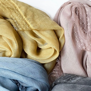 Close-up of lightweight cotton scarves in multiple colors with intricate lace borders