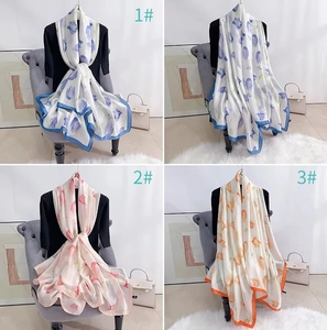 Détail de foulards en soie florale en plusieurs couleurs portés par un mannequin pour l'été