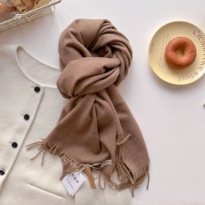 Gros plan d'une écharpe en cachemire caramel avec détails de franges et style hivernal