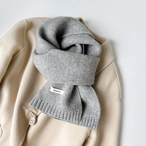 Dettaglio della sciarpa in pura lana 100% con bordo a coste su cappotto beige