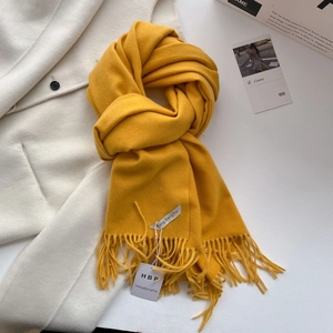 Détail d'une écharpe pashmina jaune gingembre à franges avec texture douce en cachemire
