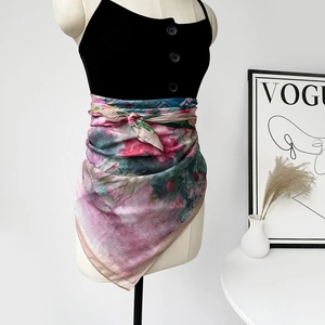 Sciarpa floreale colorata annodata con stile come accessorio in vita su un manichino