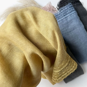 Close-up of linen scarves with delicate lace trim in yellow, blue, and gray colors