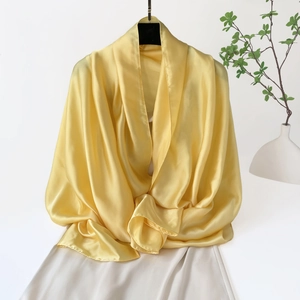 Detalle de chal de satén amarillo brillante con textura sedosa y elegante caída de tela