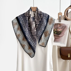 Détail d'un foulard en soie imprimé cachemire bleu marine suspendu à un cintre en bois