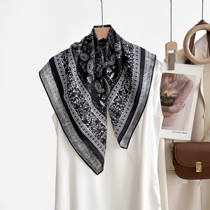 Détail du foulard en soie noir et blanc à motif cachemire drapé sur un débardeur blanc