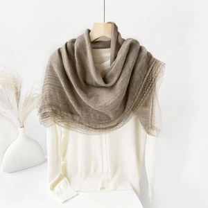Detailed close-up of light brown cotton linen shawl with delicate lace edges
