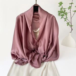 Detalle del chal de satén rosa palo con elegante caída sedosa y brillo sobre un vestido