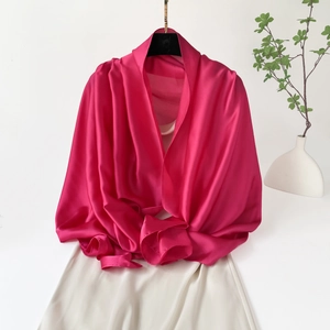 Vista detallada del chal de satén magenta con textura sedosa y caída elegante sobre ropa beige