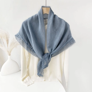Close-up of light blue cotton linen scarf with elegant lace trim on white cardigan