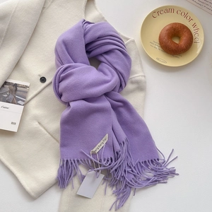 Détail d'une écharpe en cachemire imitation violette avec franges sur un manteau blanc