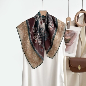 Détail d'un foulard en soie vintage à motif paisley et chevrons sur une tenue décontractée