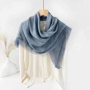 Detail of grey-blue cotton linen scarf featuring elegant lace edges on white knitwear