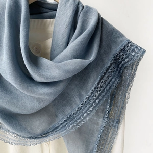 Detail of blue cotton linen scarf featuring elegant lace edges on a wooden hanger