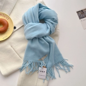 Gros plan d'une écharpe bleu clair à franges sur un manteau de laine élégant