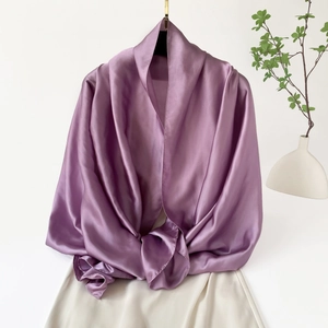 Detalle de chal de satén morado brillante con textura suave y caída elegante en percha