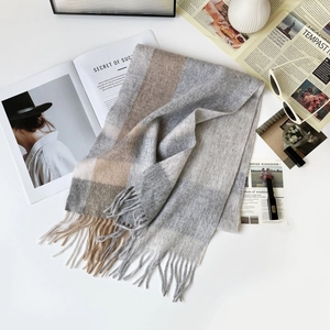 Plano detalle de bufanda de lana a cuadros gris y beige con flecos y accesorios de moda