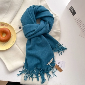 Détail d'une écharpe bleu sarcelle aspect cachemire avec texture douce et longs franges