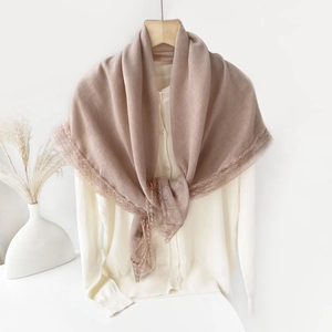 Detail of dusty pink linen scarf with delicate lace trim draped on a beige cardigan
