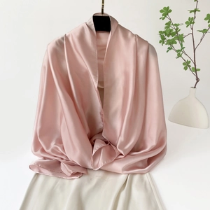 Detalle del chal de satén rosa claro con una caída elegante y textura suave y sedosa