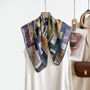 Détail d'un foulard en soie aux motifs géométriques sur une robe blanche avec sac en cuir