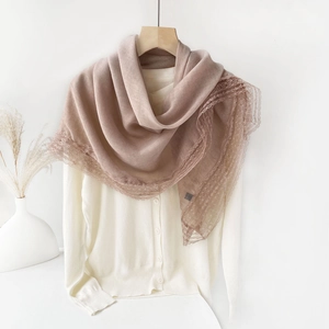 Detail of light coffee lace trim scarf draped over a white cardigan in a minimalist setup