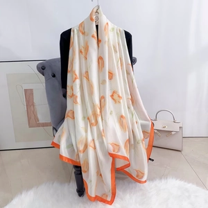 Détail d'un foulard en soie aux motifs floraux orange chaud et finitions d'ourlet orange