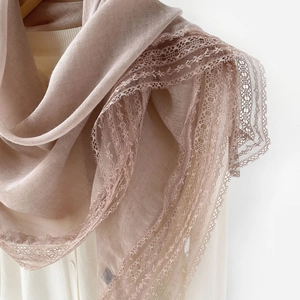 Close-up of lightweight lotus root pink scarf with elegant lace trim on white shirt
