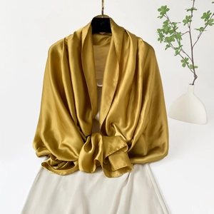 Detalle de un elegante chal de satén dorado con textura sedosa y brillo suave