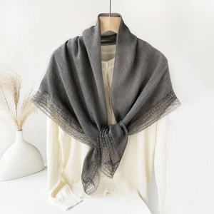 Detailed view of dark grey shawl with elegant lace trim over a cream knit cardigan