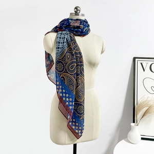 Dettaglio di un foulard in seta blu navy con eleganti motivi paisley gialli e mandala